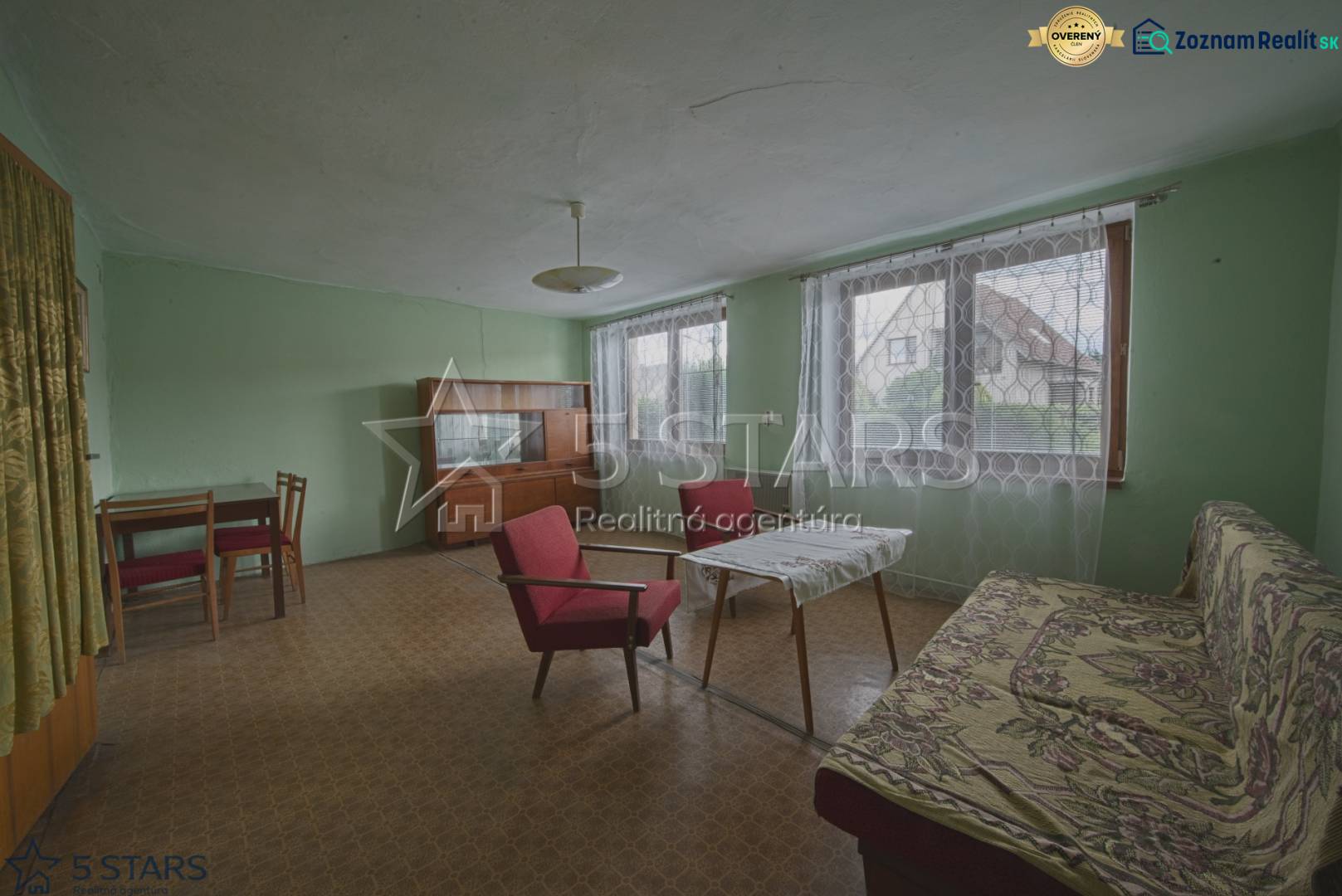 Pokoj v rodinném domě s nábytkem, křesly a stolem, podlaha s dřevěným dekorem.