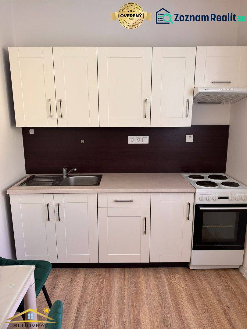 Kuchyňská linka v 1-pokojovém bytě s umyvadlem, sporákem a úložným prostorem.