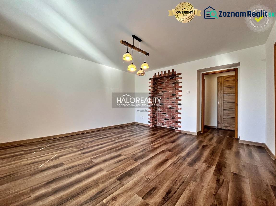 Obývací pokoj v 3-pokojovém bytě s podlahou s dřevěným dekorem a cihlovou stěnou.