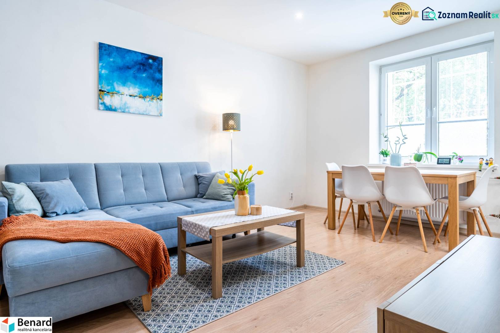 Obývací pokoj v 3-pokojovém bytě s pohovkou a jídelním stolem, podlaha s dřevěným dekorem.