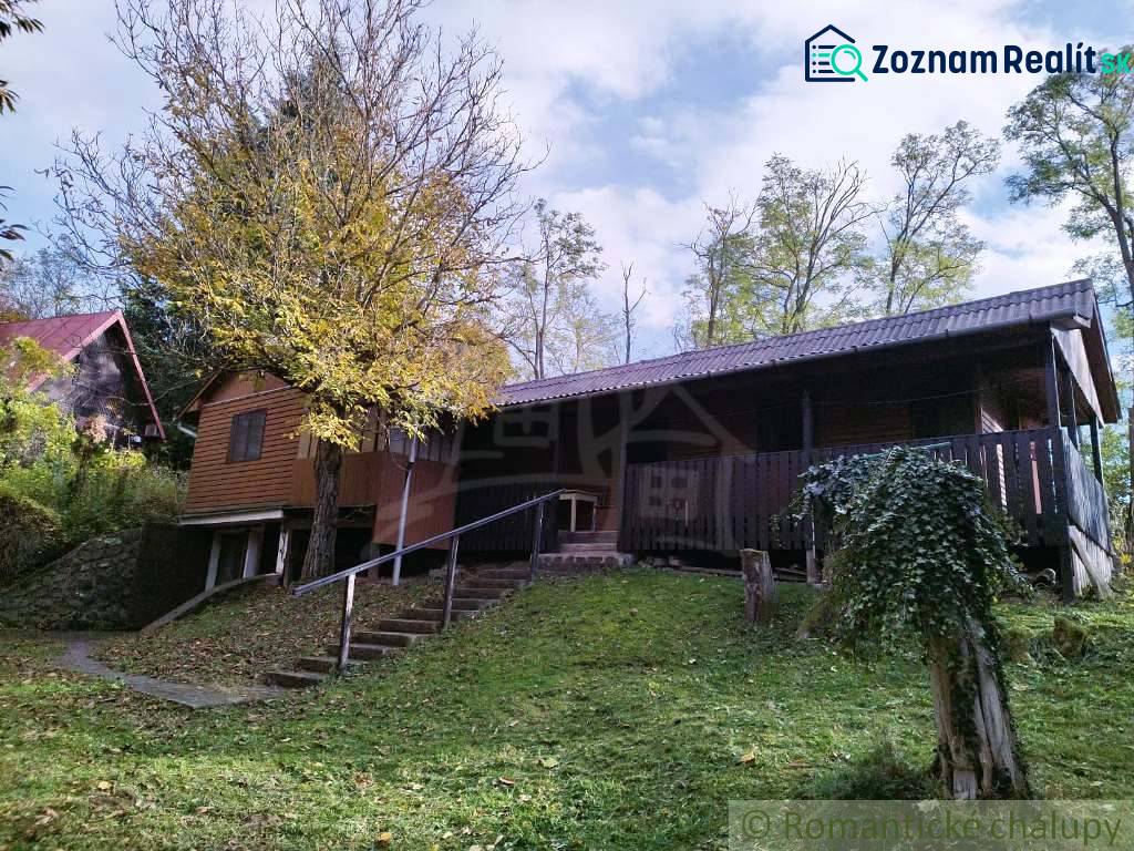 Chata v Dudincích obklopená přírodou s terasou a stromy na dvoře.