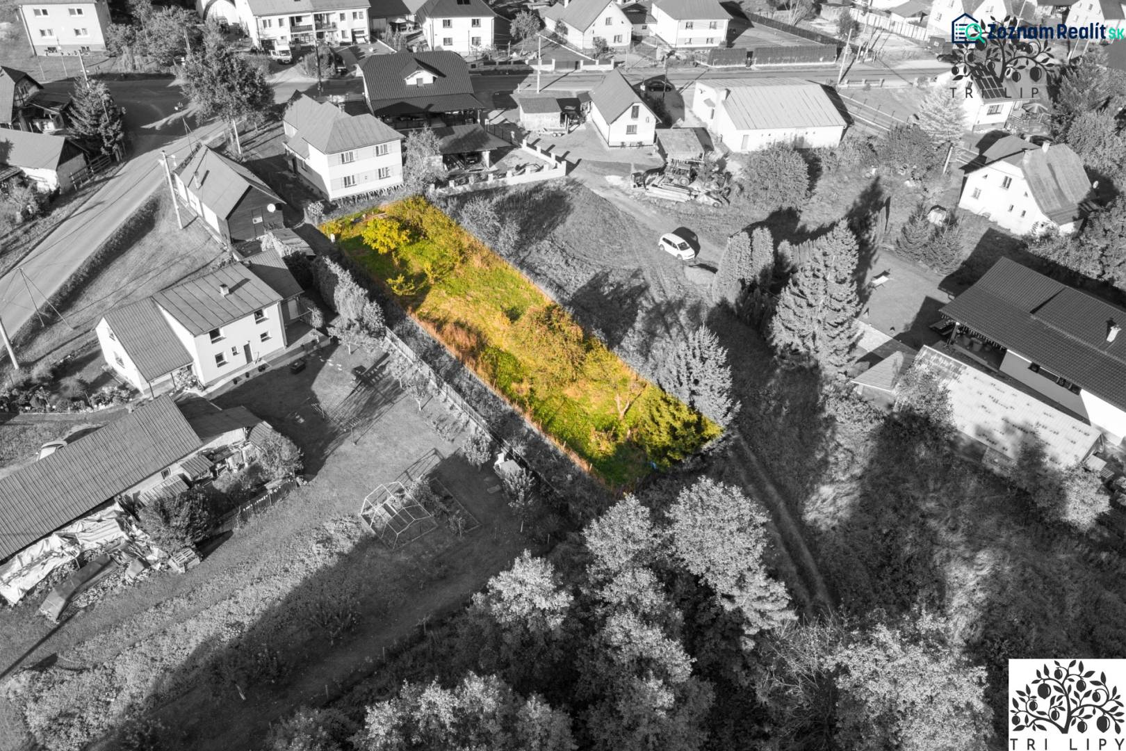 Pozemek k bydlení v Turzovce, obklopený domy, s travnatým porostem a stromy.