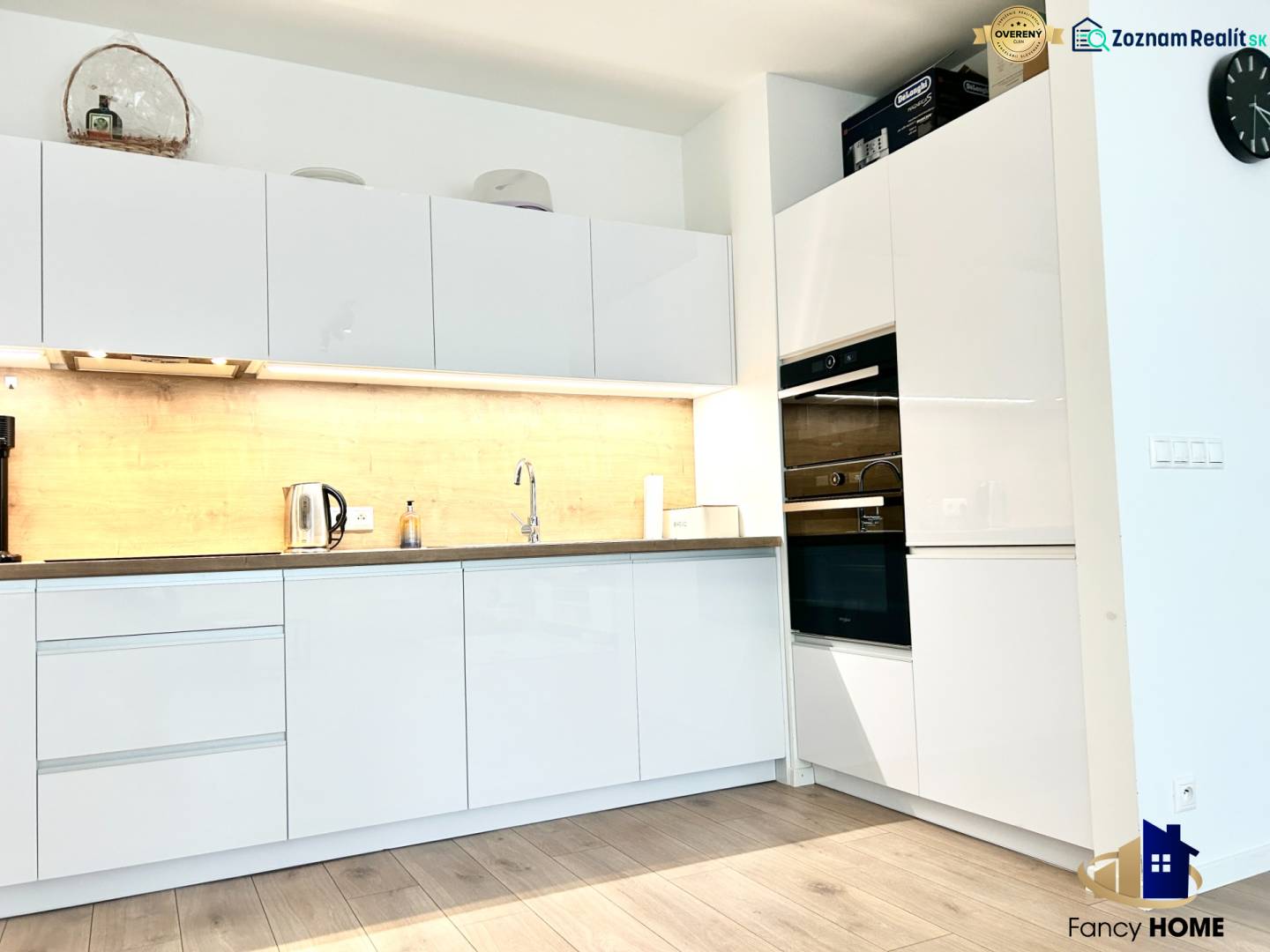 Kuchyně v 2-pokojovém bytě s bílými skříňkami a podlahou s dřevěným dekorem.