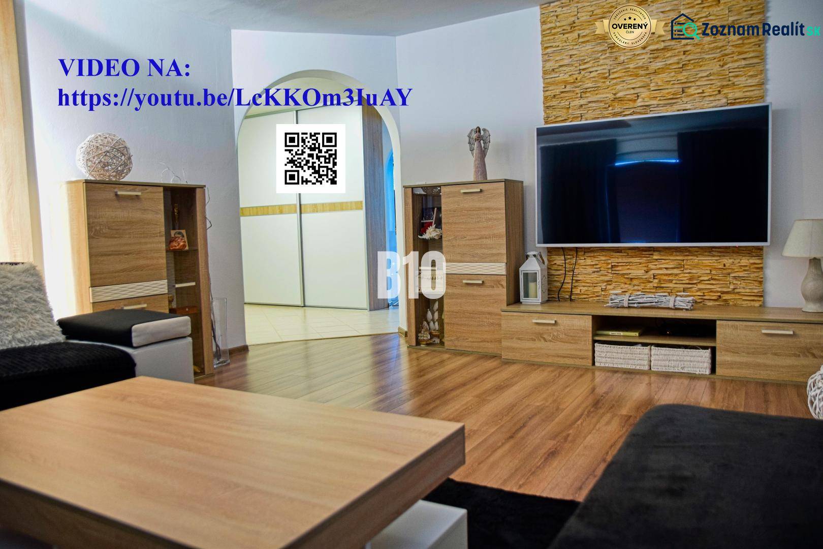 Obývací pokoj v rodinném domě s televizí, dřevěným nábytkem a podlahou s dřevěným dekorem.