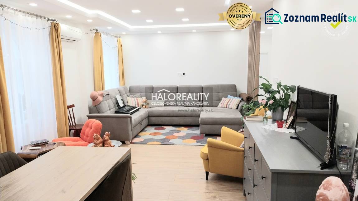 Obývací pokoj v 3-pokojovém bytě s podlahou s dřevěným dekorem, šedou sedačkou a žlutým křeslem.