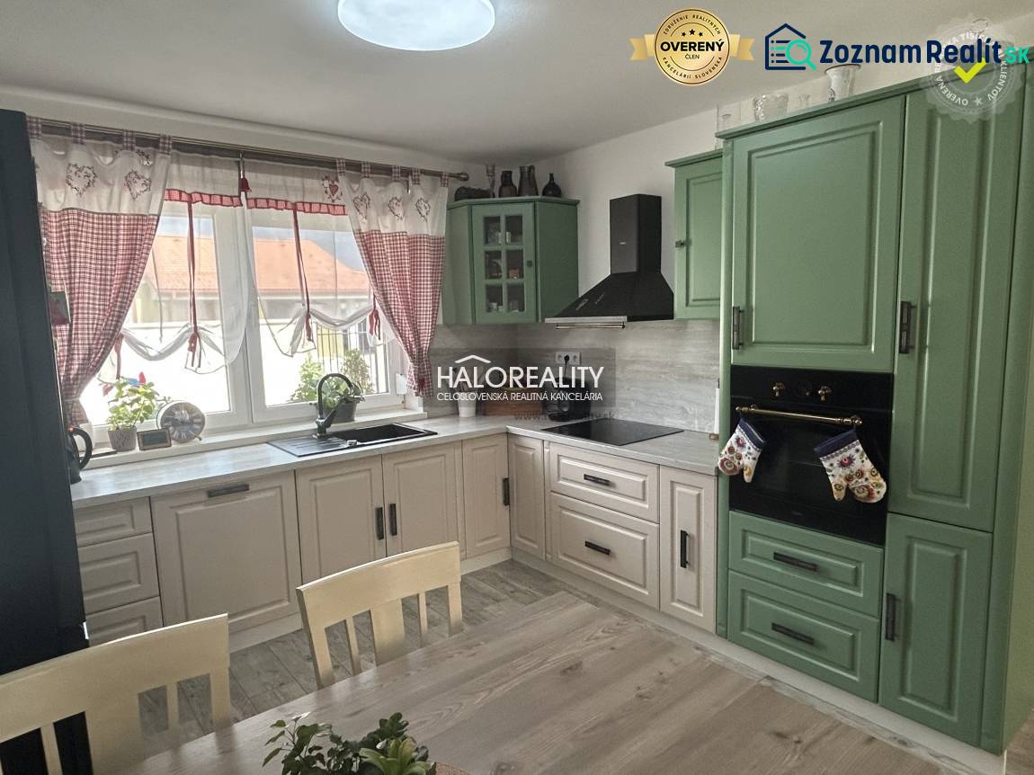 Kuchyně v rodinném domě s dřevěným nábytkem a závěsy.