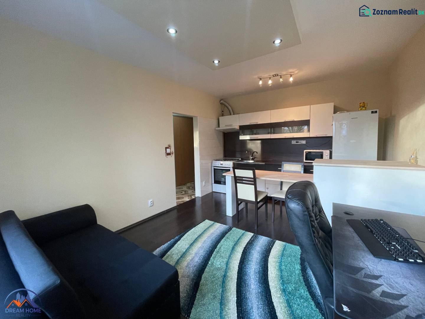 Interiér 1-pokojového bytu s kuchyňským koutem a podlahou s dřevěným dekorem.