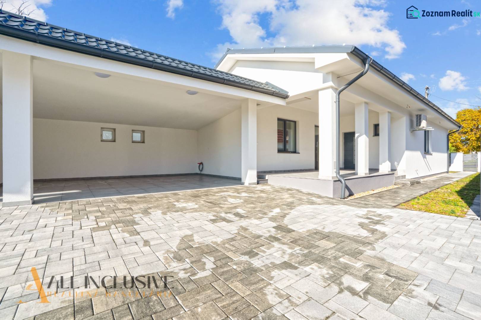 Rodinný dům v Orechové Potôni s terasou a garážovým přístřeškem na dlažbě.