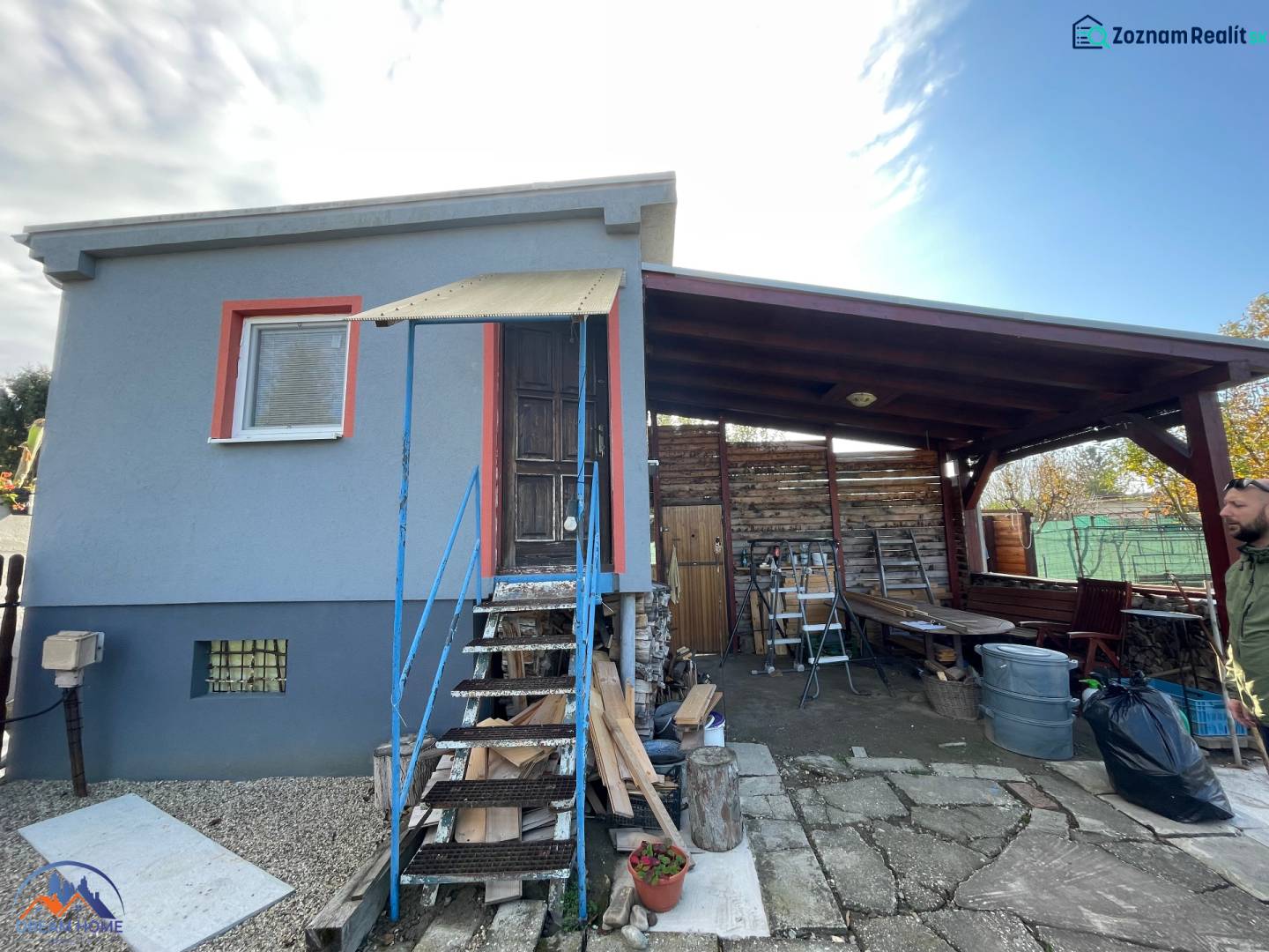 Chata v Komárně na ulici Nové osady s krytou terasou a dřevěným schodištěm.