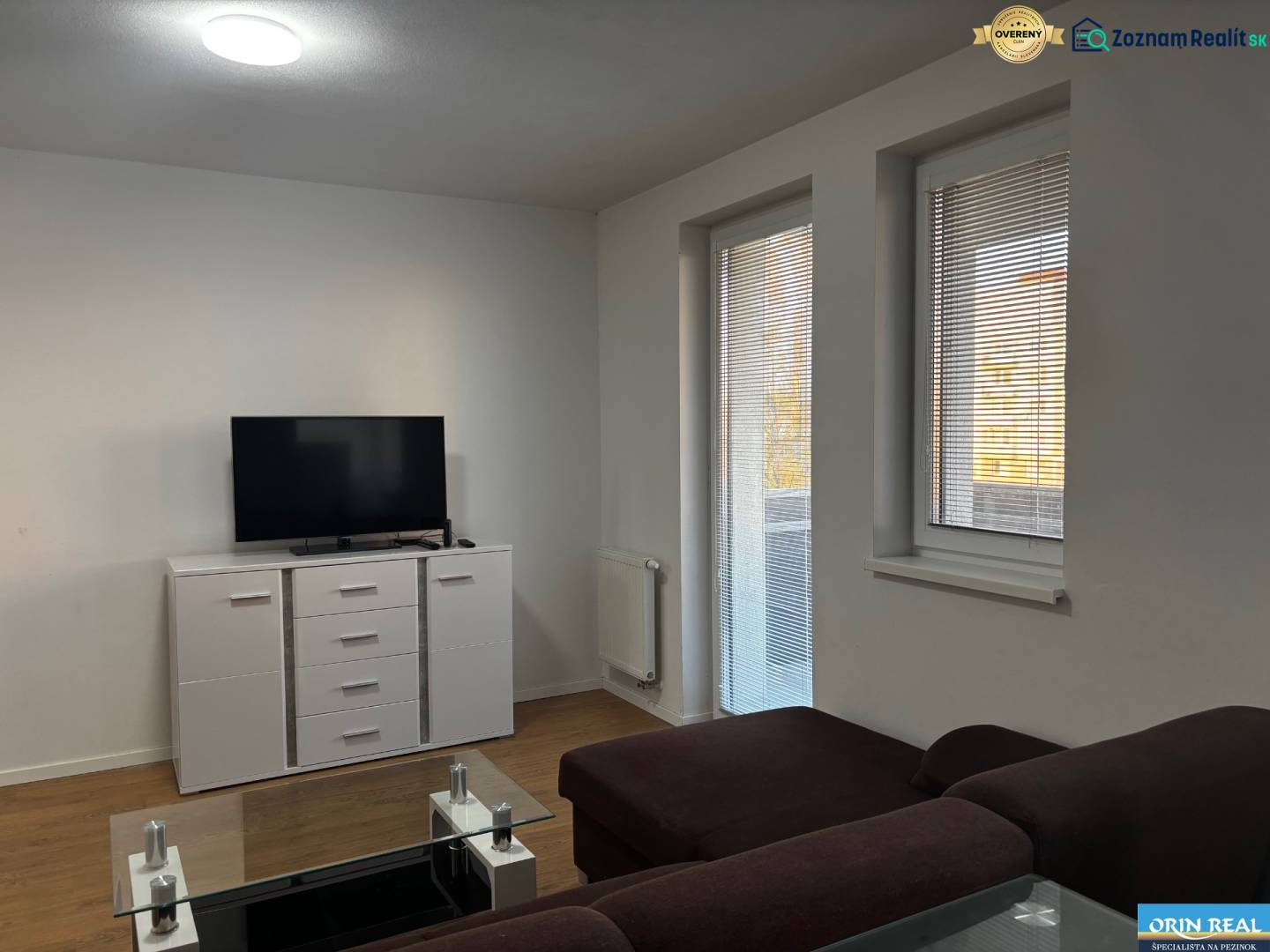 Obývací pokoj v 2-pokojovém bytě s pohovkou, televizorem a podlahou s dřevěným dekorem.