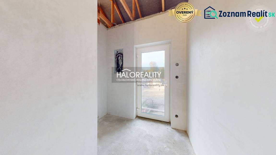 Světlá místnost v rodinném domě s betonovou podlahou a skleněnými dveřmi.