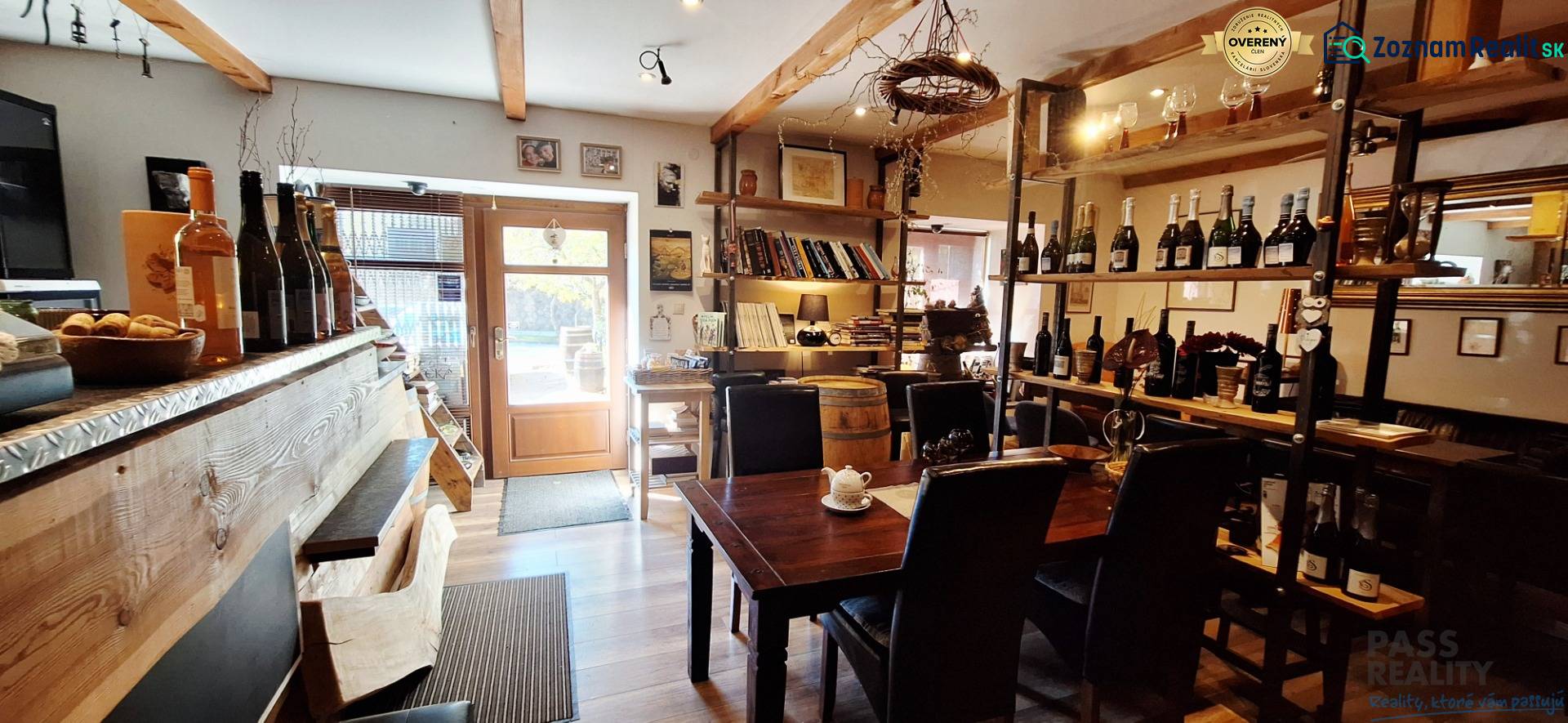 Interiér obchodních prostor s barem, stolem a vinnými policemi, podlaha s dřevěným dekorem.