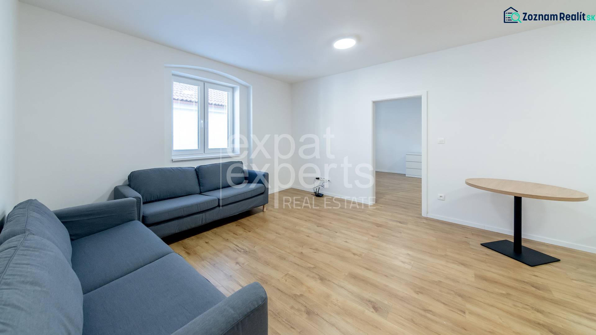 Obývací pokoj s modrými pohovkami a stolem na podlaze s dřevěným dekorem.