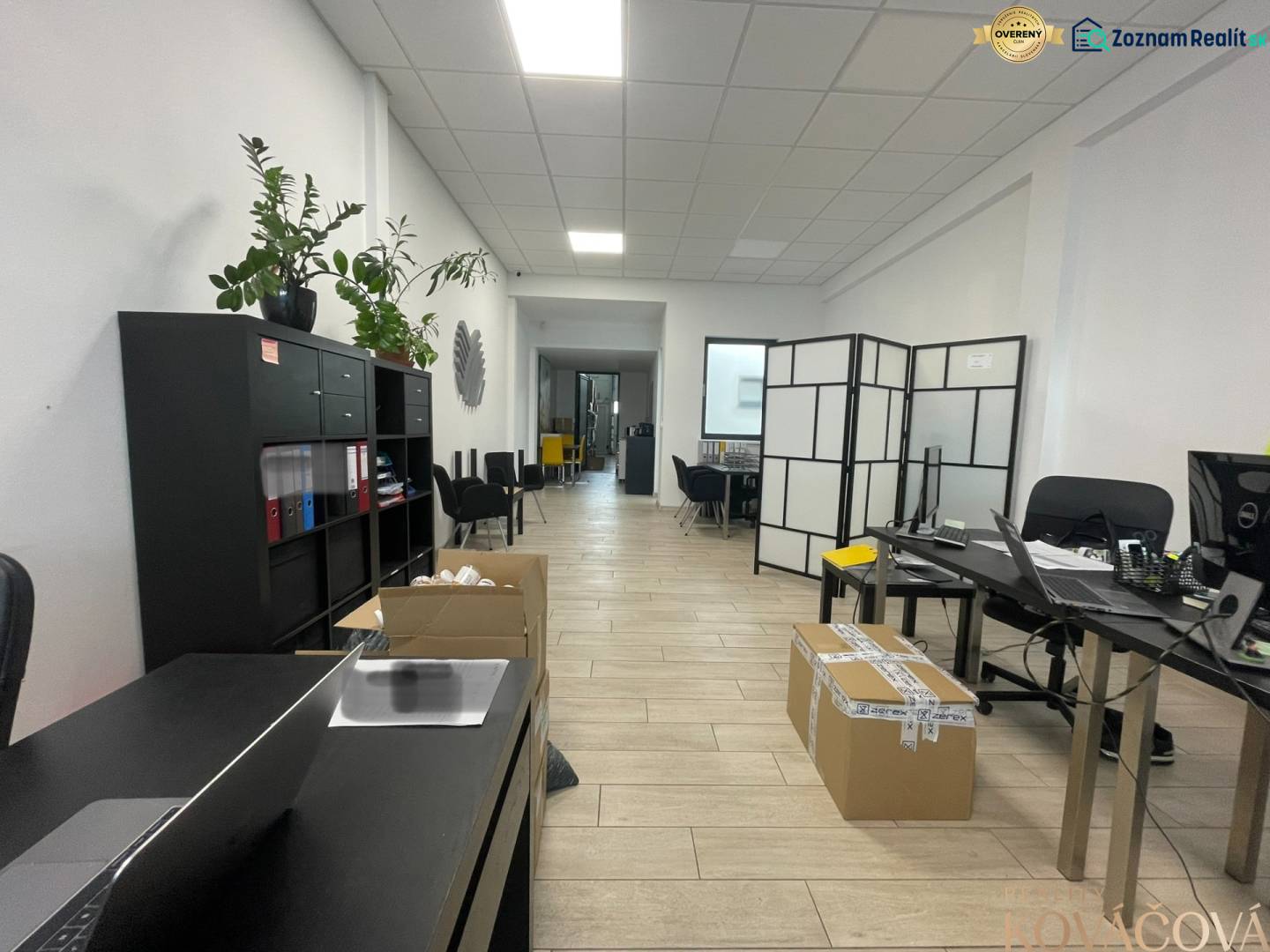 Obchodní prostory s poličkou, stoly, křesly a podlahou s dřevěným dekorem.