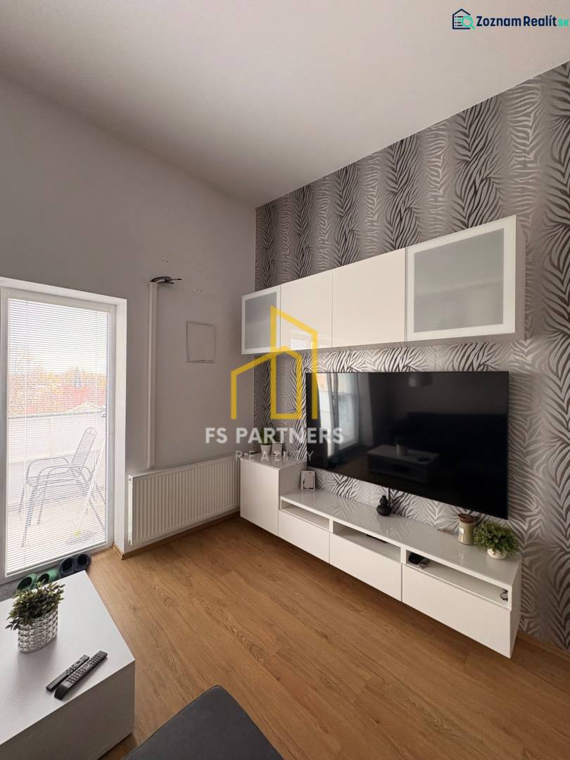 Obývací pokoj s TV stěnou, vzorovanou tapetou a podlahou s dřevěným dekorem v 2pokojovém bytě.