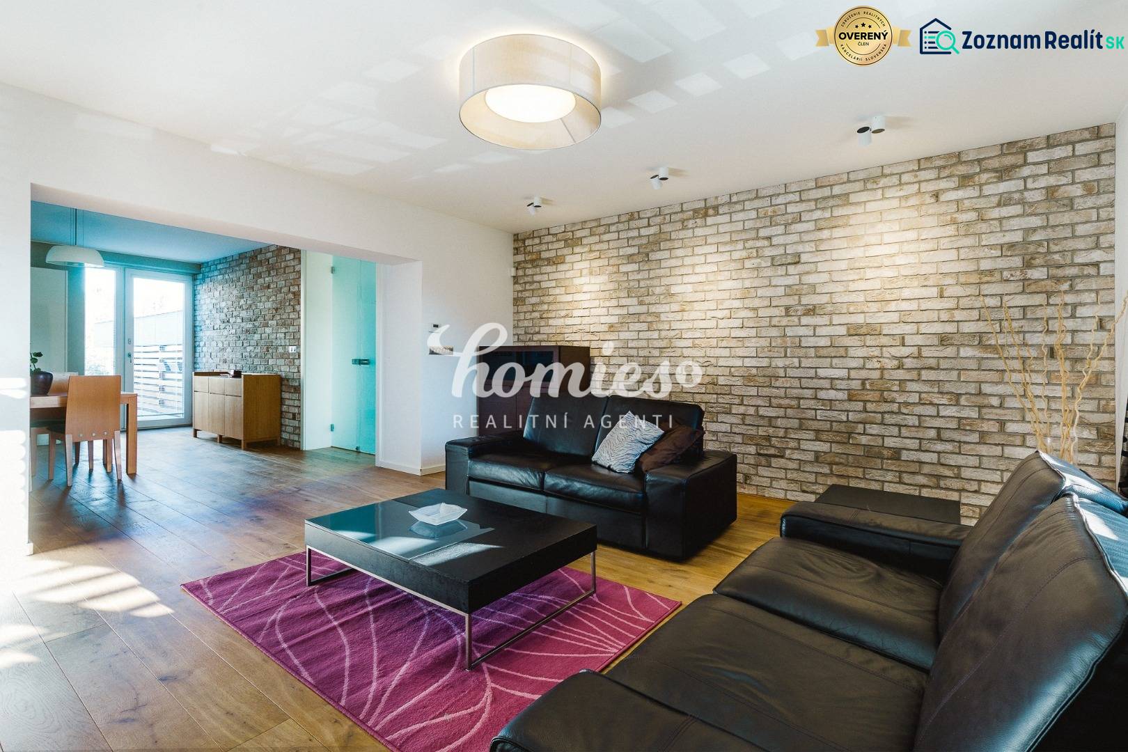 Obývací pokoj v rodinném domě s cihlovou stěnou a podlahou s dřevěným dekorem.