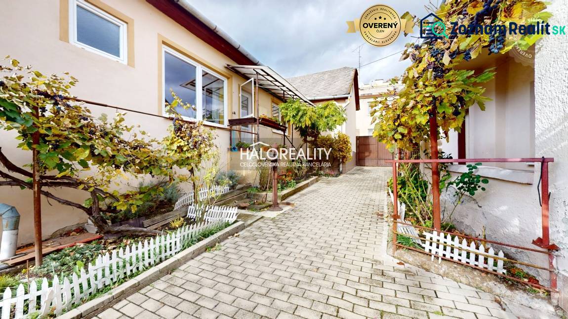 V Lučenci rodinný dům s terasou, zahrádkou a vinnou révou na dlážděné cestičce.