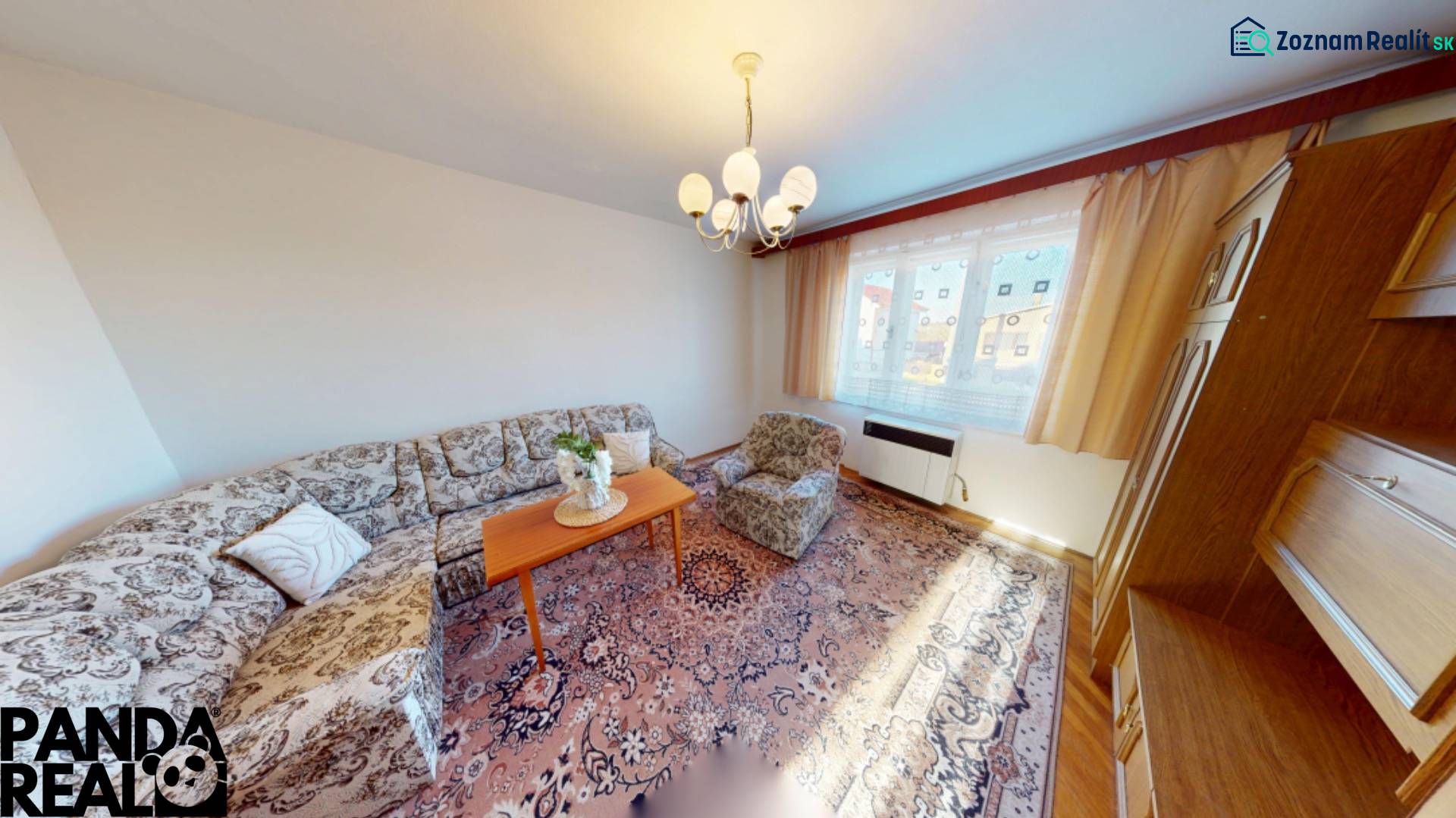 Obývací pokoj v rodinném domě s pohovkou, kobercem a dřevěnými skříněmi.