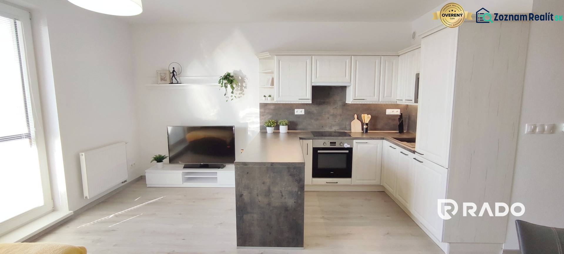 Obývací pokoj s kuchyňským koutem, světlá podlaha s dřevěným dekorem v 2-pokojovém bytě.