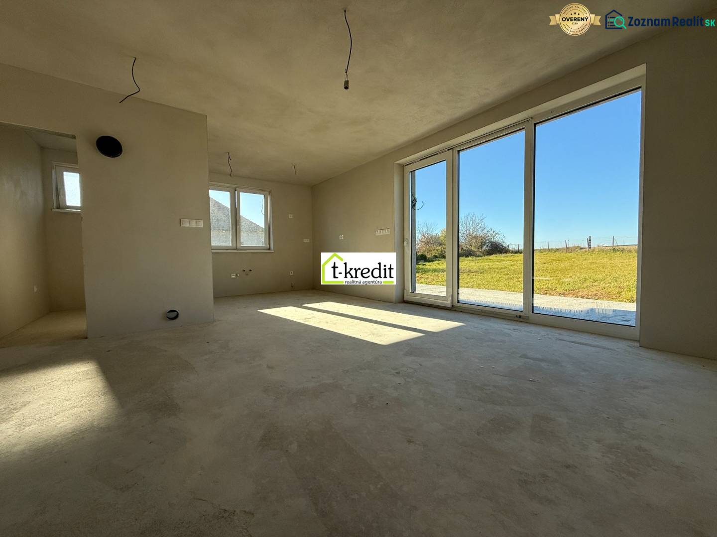 Prostorný interiér rodinného domu s velkými okny a výhledem na zahradu.