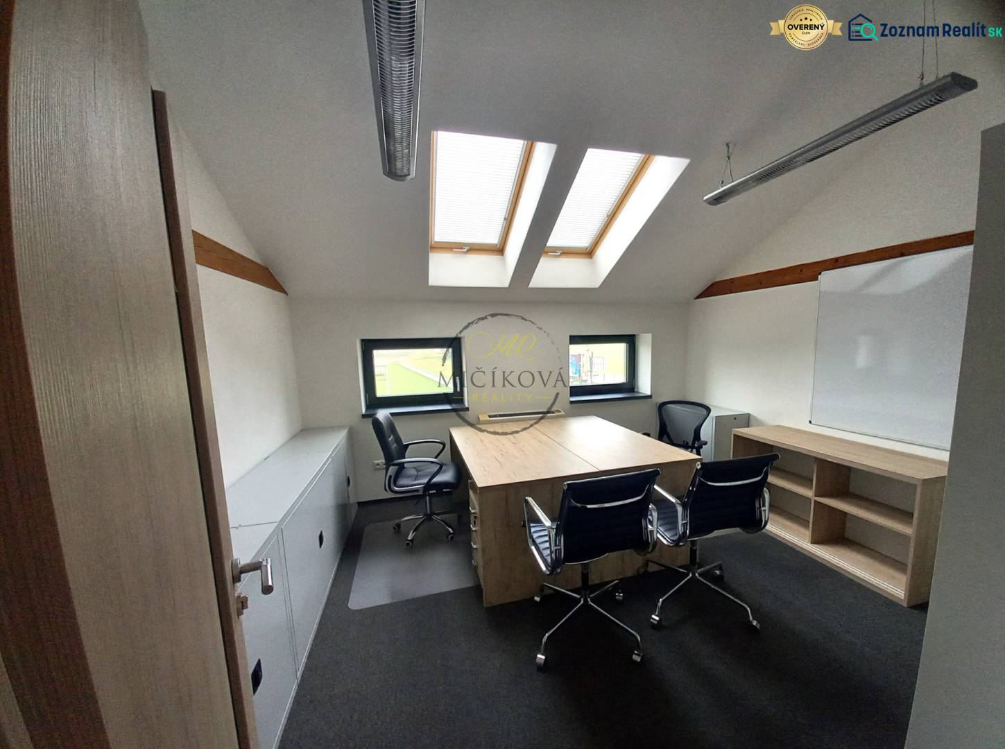 Kancelář s podlahou s dřevěným dekorem, střešními okny a stoly se židlemi.
