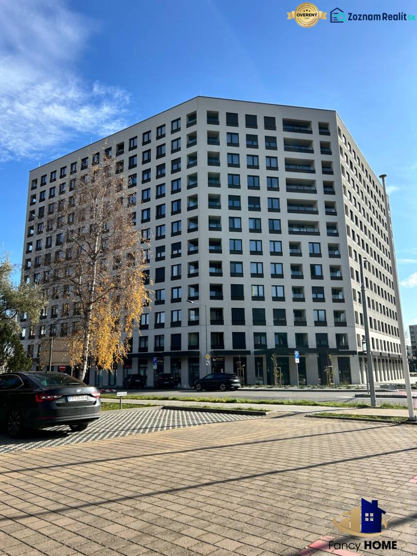 Bytový dům na Karpatské ulici v Popradu, okolní parkoviště a stromy.