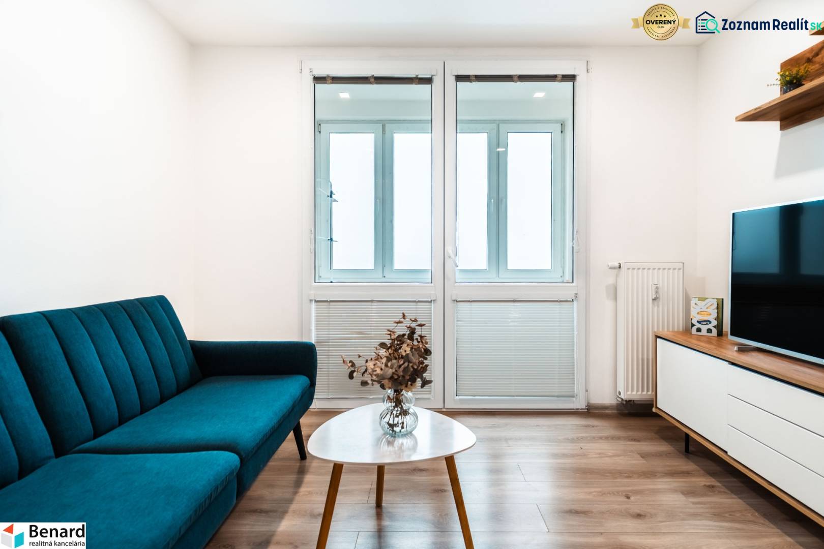 Obývací pokoj v 2-pokojovém bytě s pohovkou, televizorem a podlahou s dřevěným dekorem.