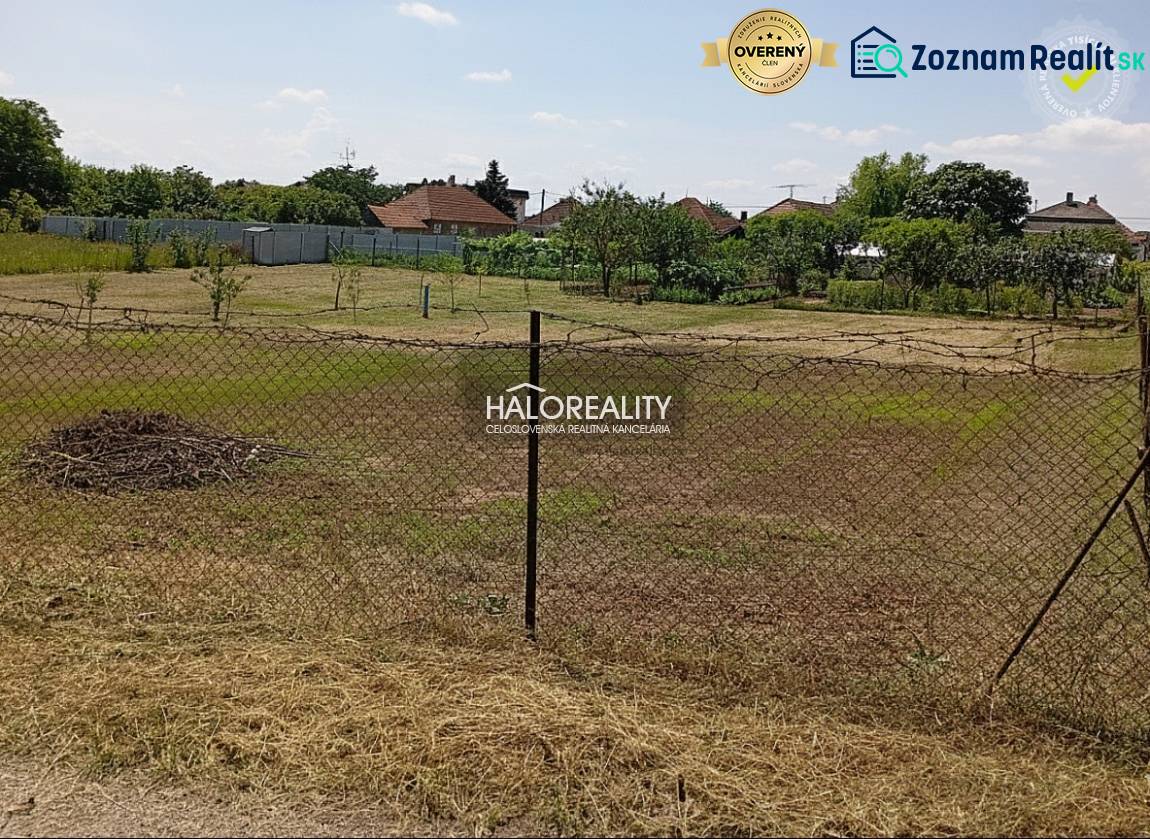 Zahrady v Marcelové s travnatým povrchem a oplocením, stromy v pozadí.