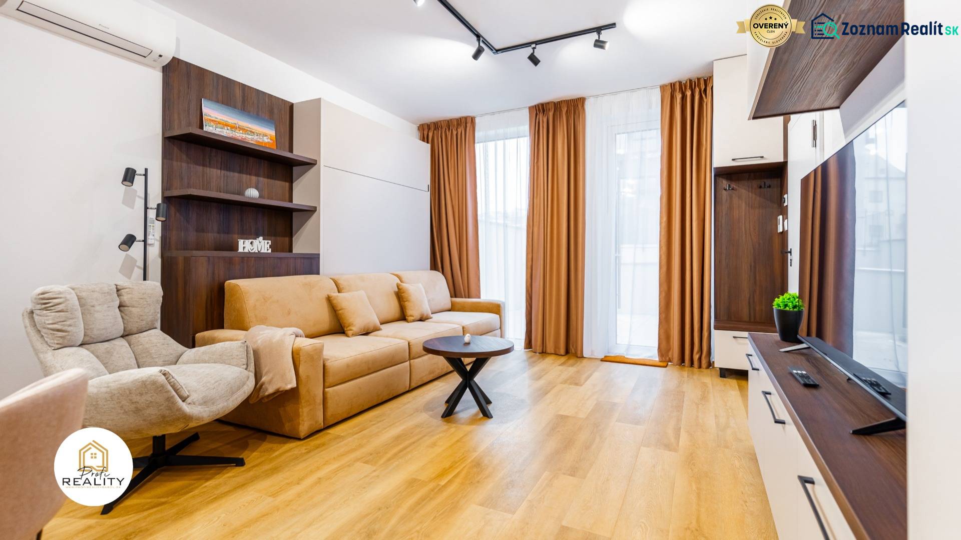 Obývací pokoj s pohovkou, křeslem a podlahou s dřevěným dekorem v 1+kk bytě.