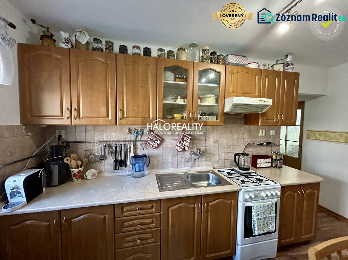 Kuchyně v 2-pokojovém bytě s dřevěným dekorem na podlaze a dřevěnými skříňkami.