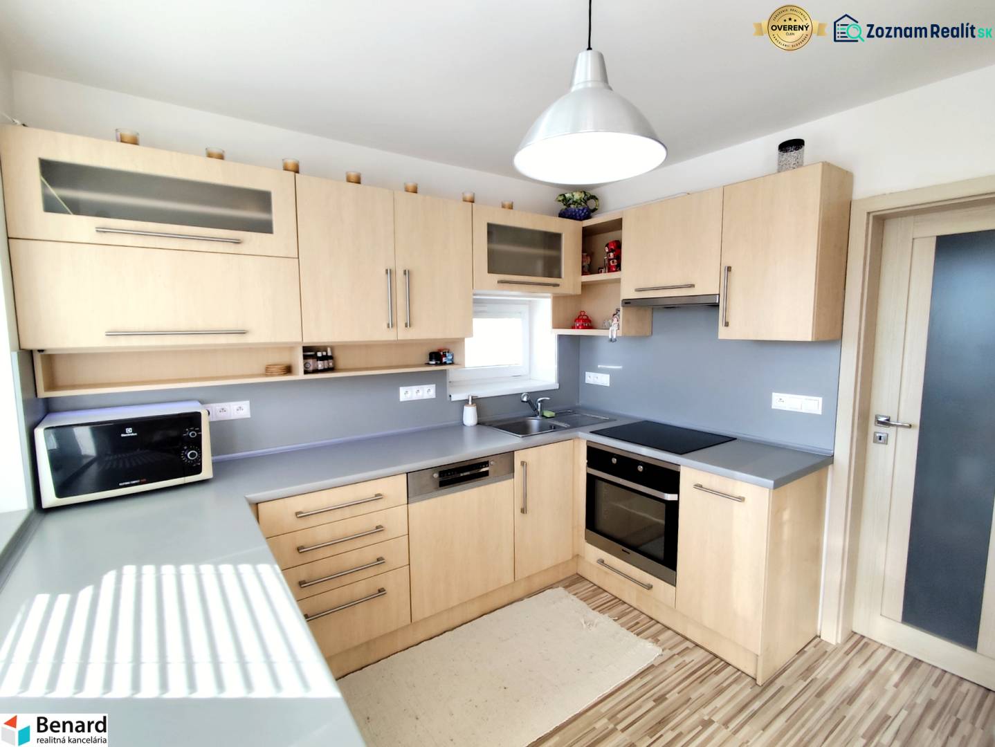 Kuchyně v rodinném domě s dřevěným dekorem a šedou pracovní deskou.