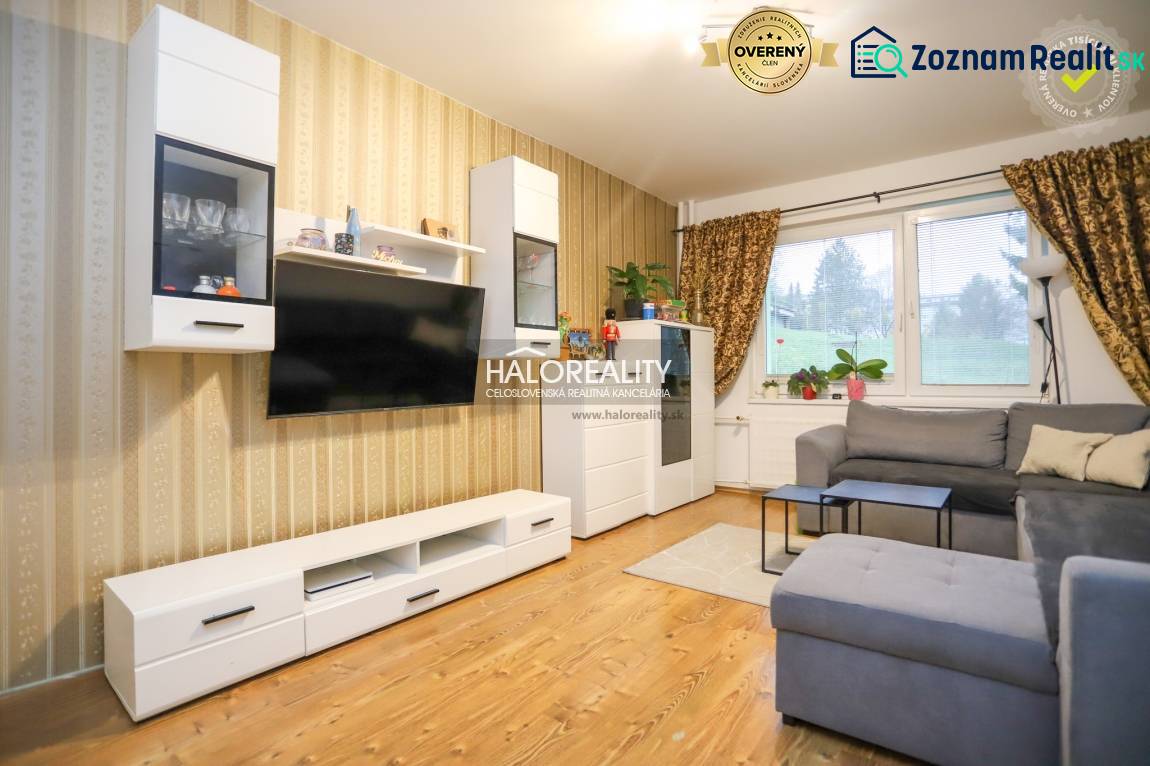 Obývací pokoj v 2-pokojovém bytě s podlahou s dřevěným dekorem a pohodlnou sedačkou.