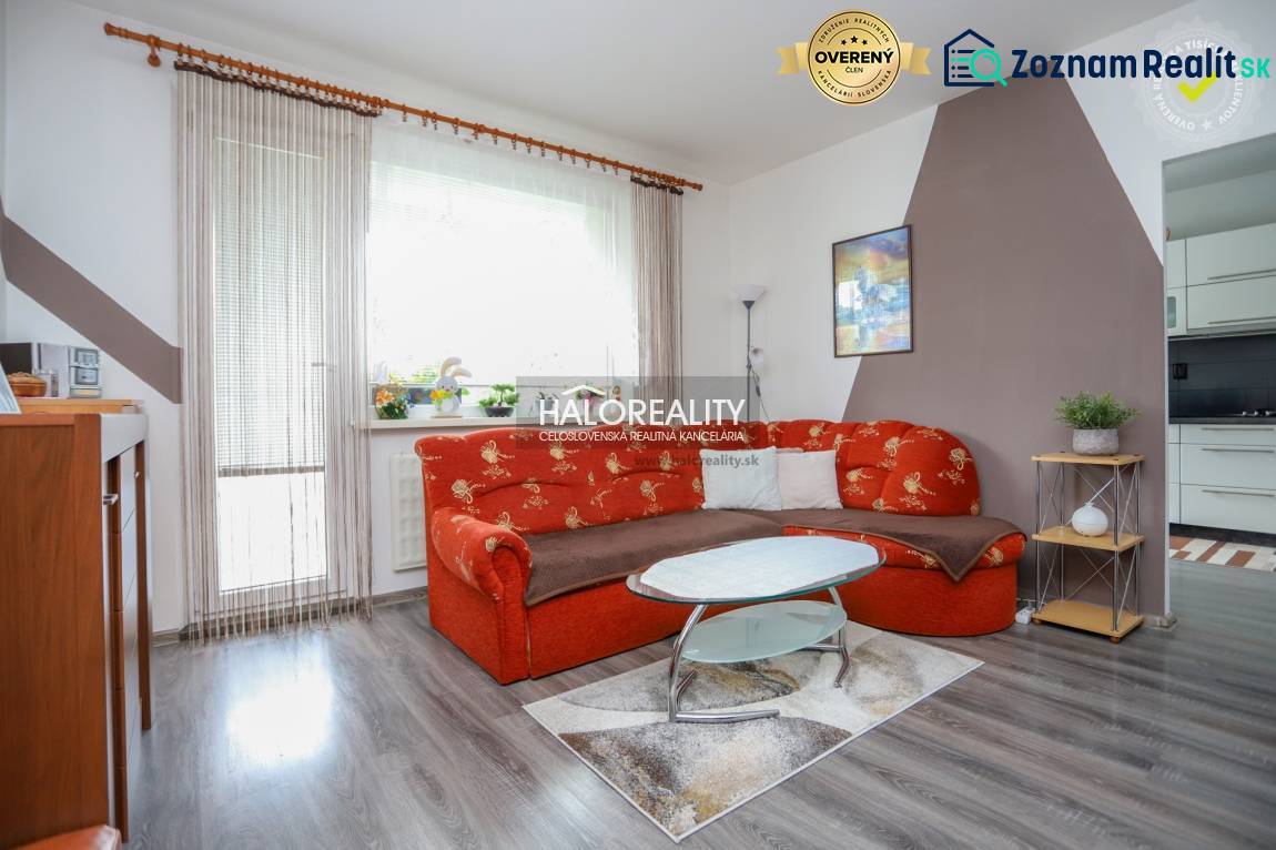 Obývací pokoj v 3-pokojovém bytě s oranžovou sedačkou a podlahou s dřevěným dekorem.
