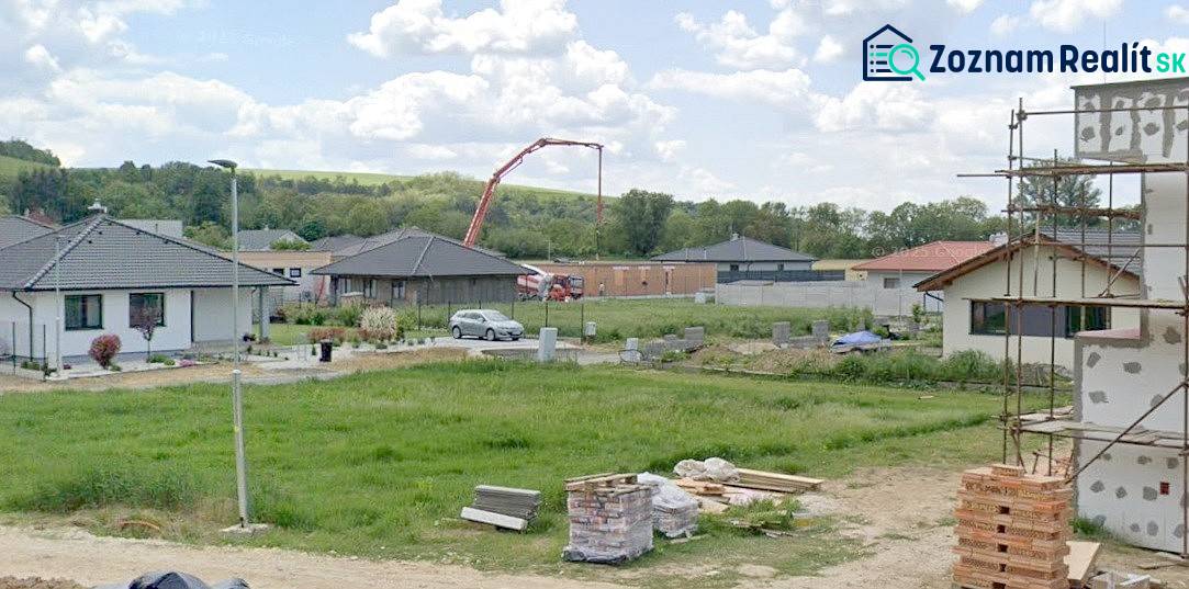 Pozemky - bydlení v Modrovce; vidět rozestavěné domy a stavební materiál.