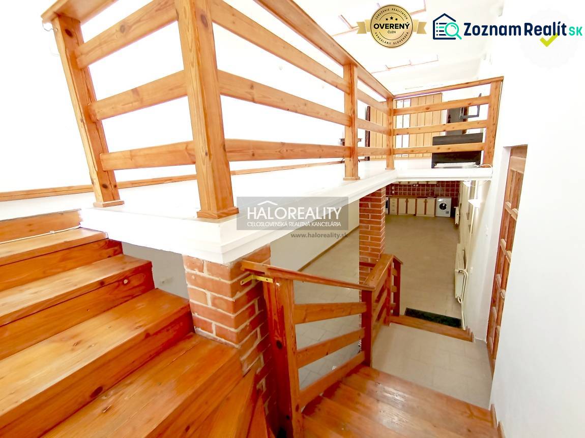 Dřevěné schody a zábradlí v rodinném domě s cihlovým detailem na stěně.