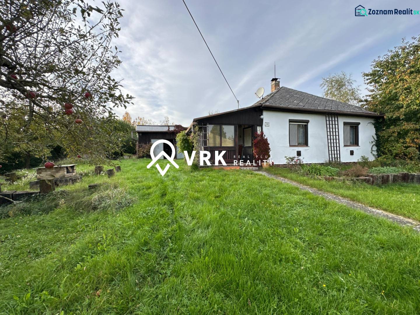 Rodinný dům v Kalši obklopený zahradou a ovocnými stromy, s upraveným trávníkem.