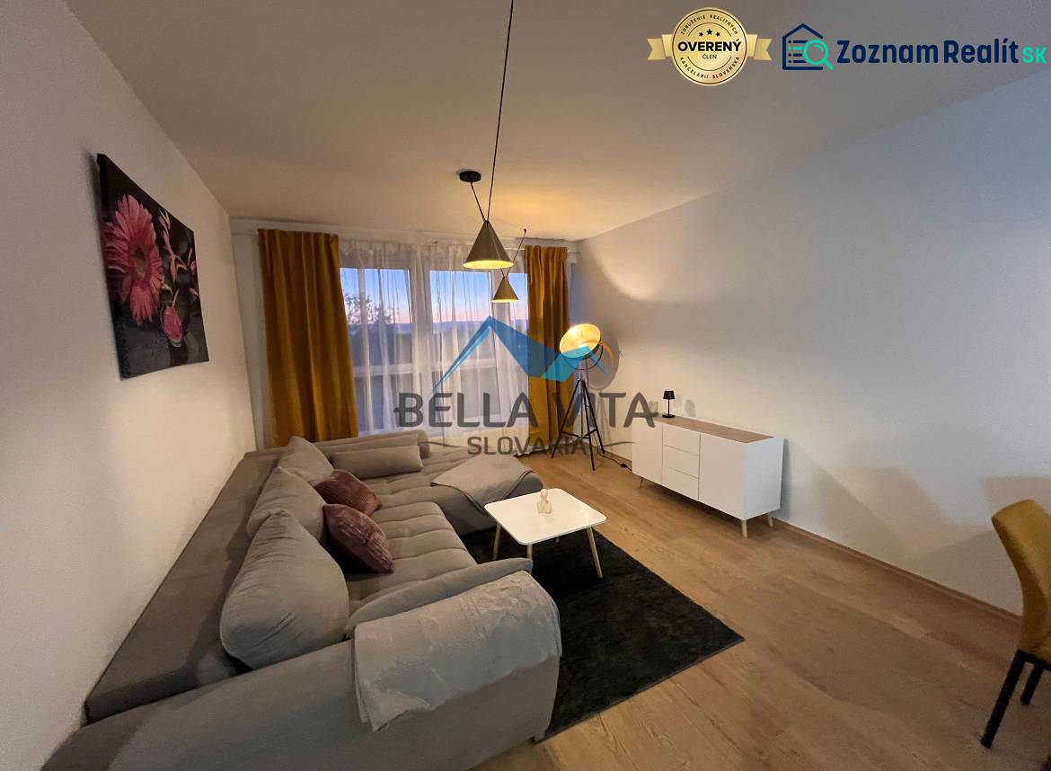 Obývací pokoj v 2pokojovém bytě s pohovkou a podlahou s dřevěným dekorem.