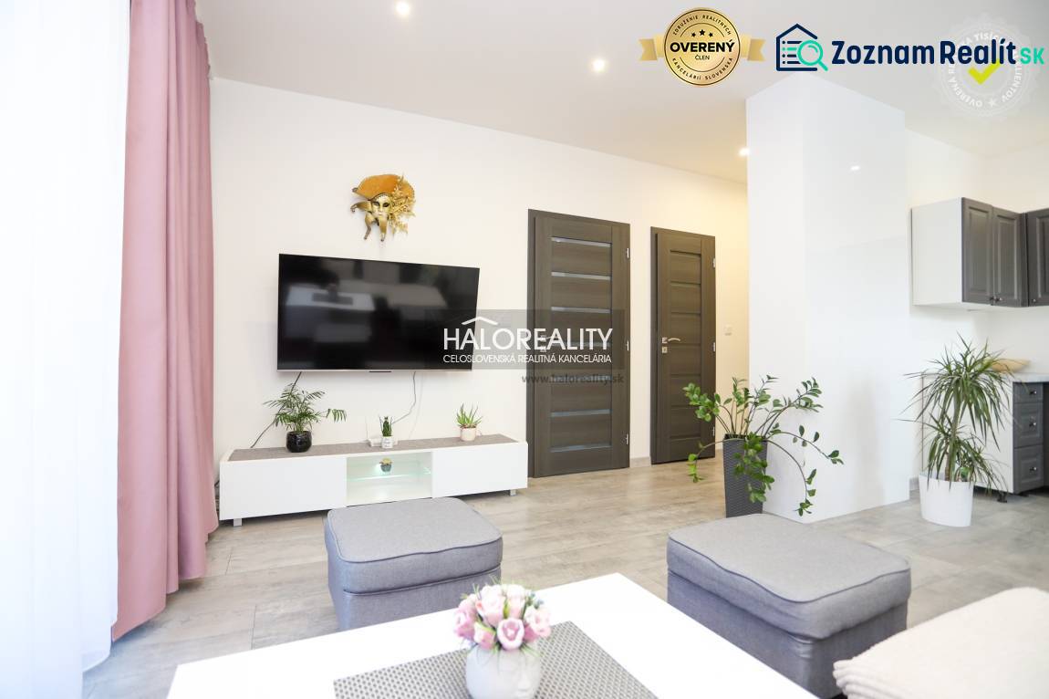 Obývací pokoj v 2pokojovém bytě s televizí, rostlinami a podlahou s dřevěným dekorem.