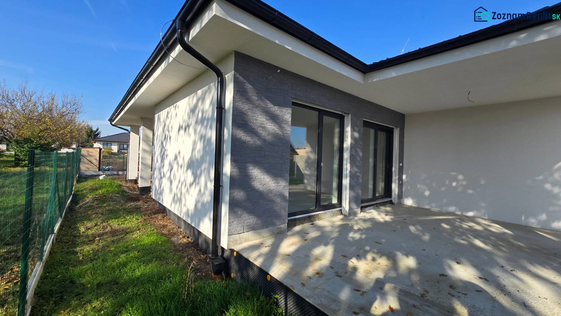 Rodinný dům v Piešťanech s terasou a zahradou, ohraničenou zeleným plotem.