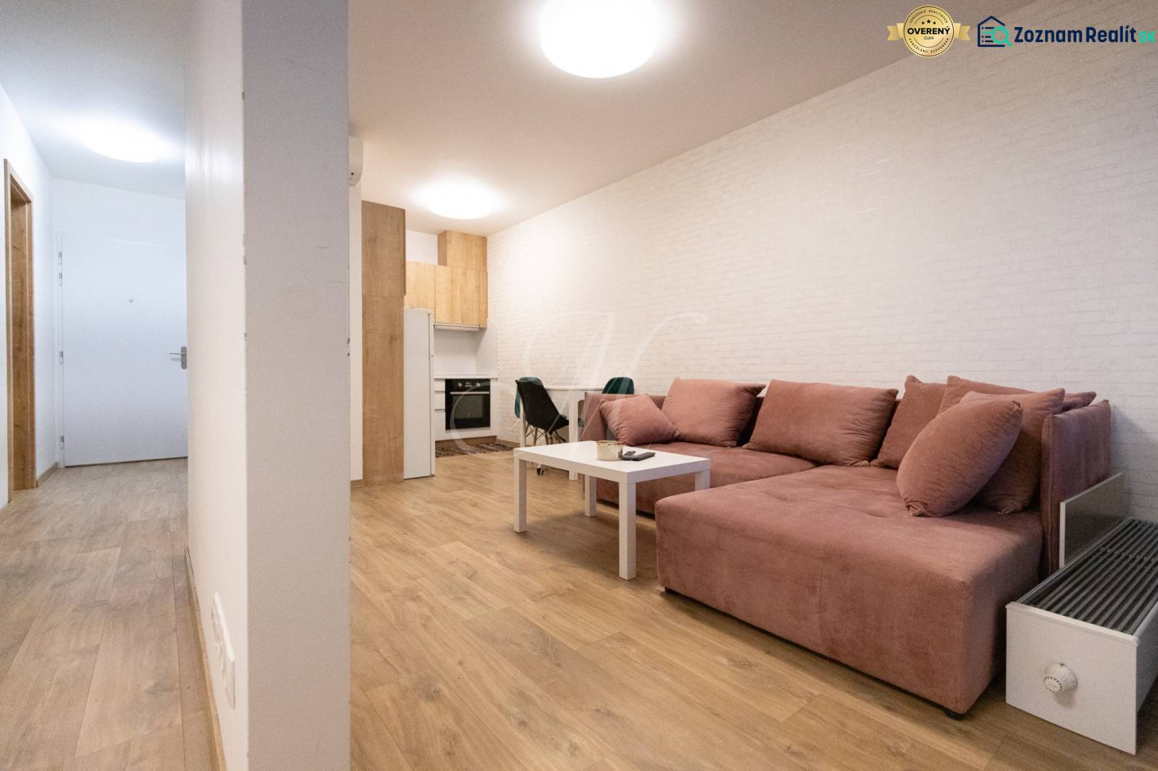 Obývací pokoj v 2-pokojovém bytě s pohodlnou sedačkou a podlahou s dřevěným dekorem.