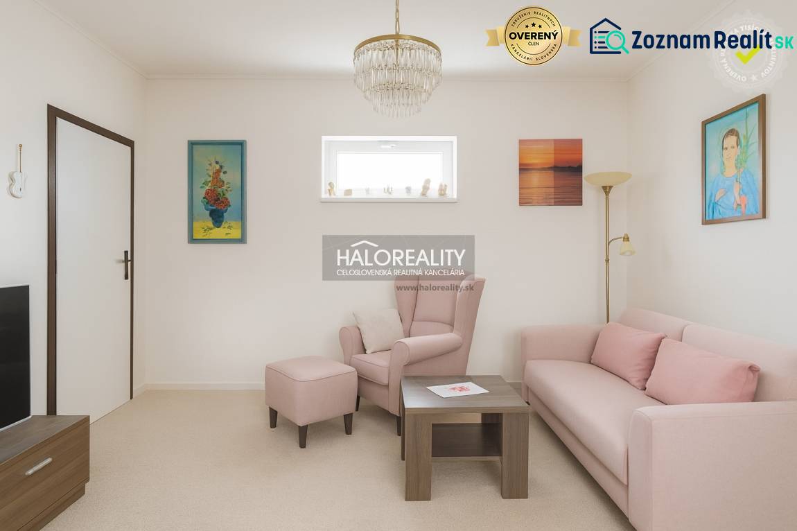 Obývací pokoj s pastelovou sedačkou a křeslem v rodinném domě, dekorativní obrazy na stěnách.