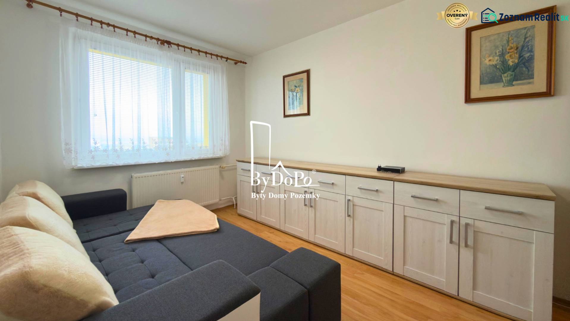 Pokoj s pohovkou, nábytkem a podlahou s dřevěným dekorem ve 3pokojovém bytě.