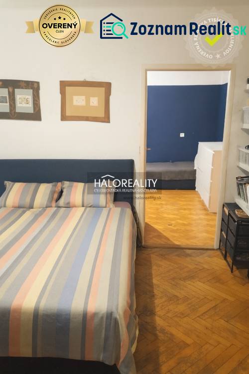 Ložnice v 3-pokojovém bytě s podlahou s dřevěným dekorem a barevným ložním prádlem.