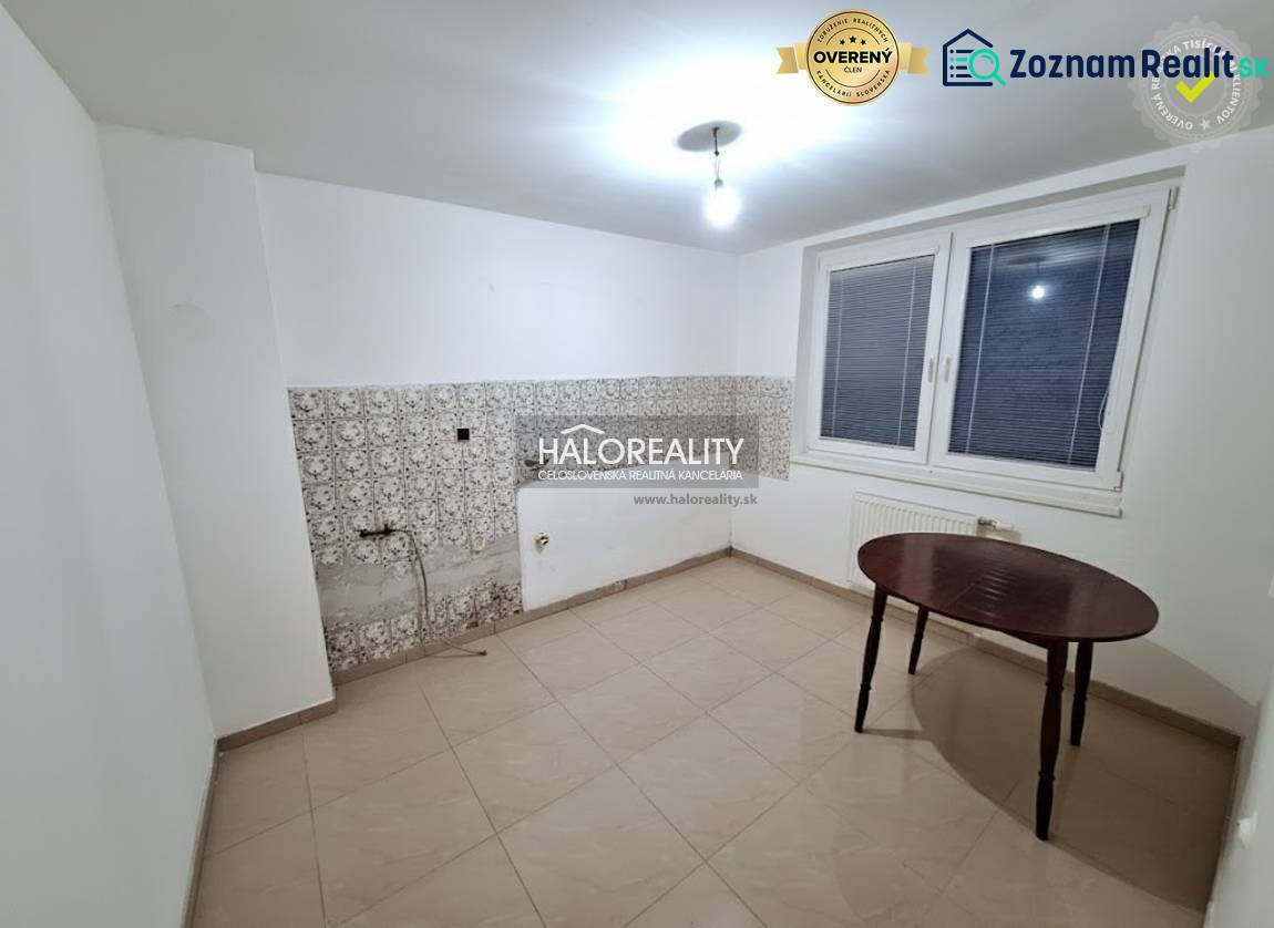 Pokoj v rodinném domě s bílými stěnami, oknem a dlaždicemi.