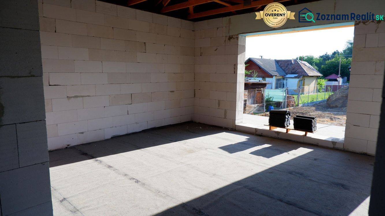 Stavba rodinného domu v Radavě s pohledem na neomítnuté stěny a okolní krajinu.