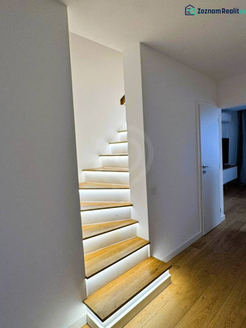 Schodiště v rodinném domě se zabudovaným osvětlením a podlahou s dřevěným dekorem.