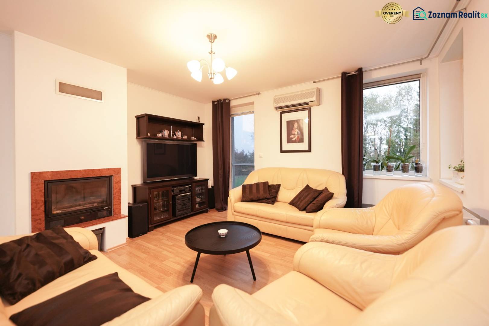 Obývací pokoj v rodinném domě s krbem, koženými sedačkami a podlahou s dřevěným dekorem.