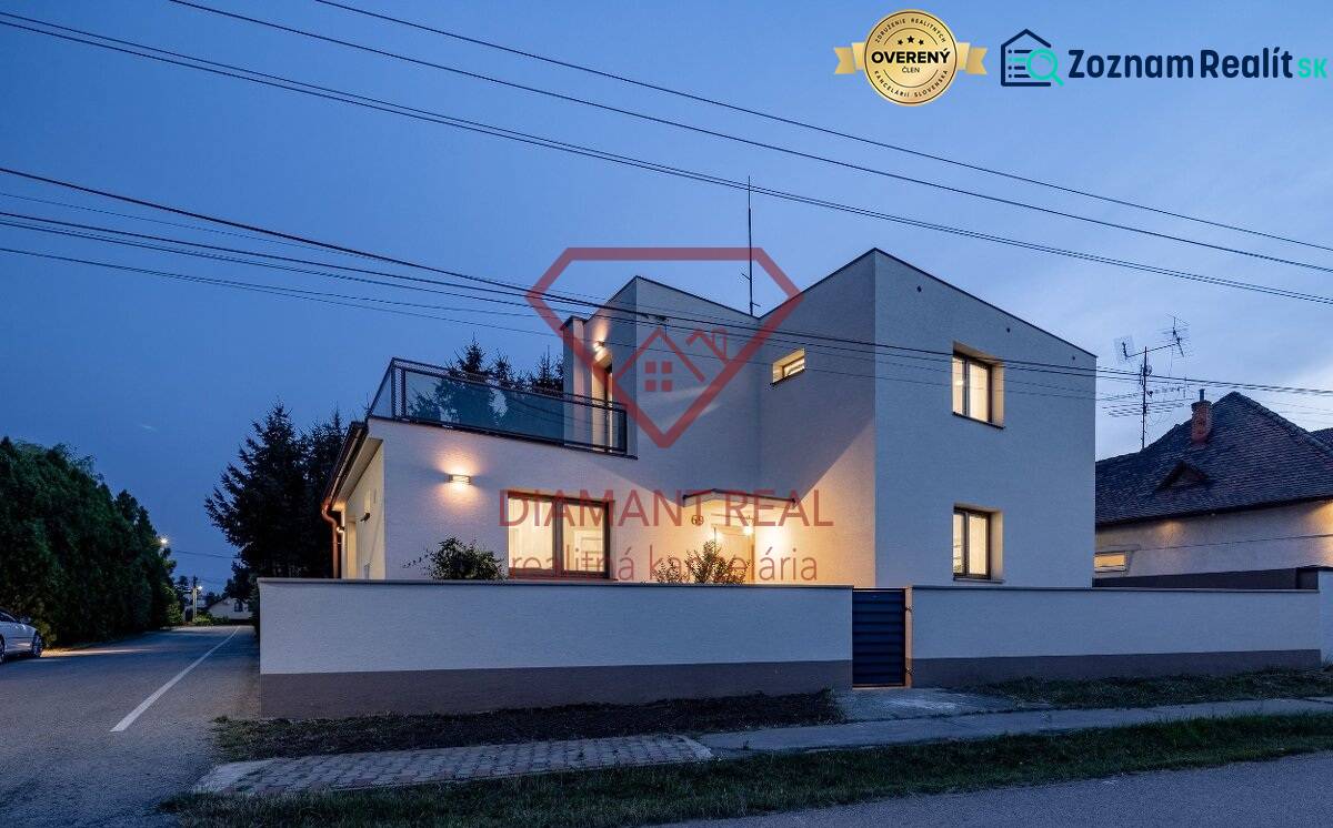 Rodinný dům na Trnovecké ulici v Trnovci nad Váhom osvětlený za soumraku.