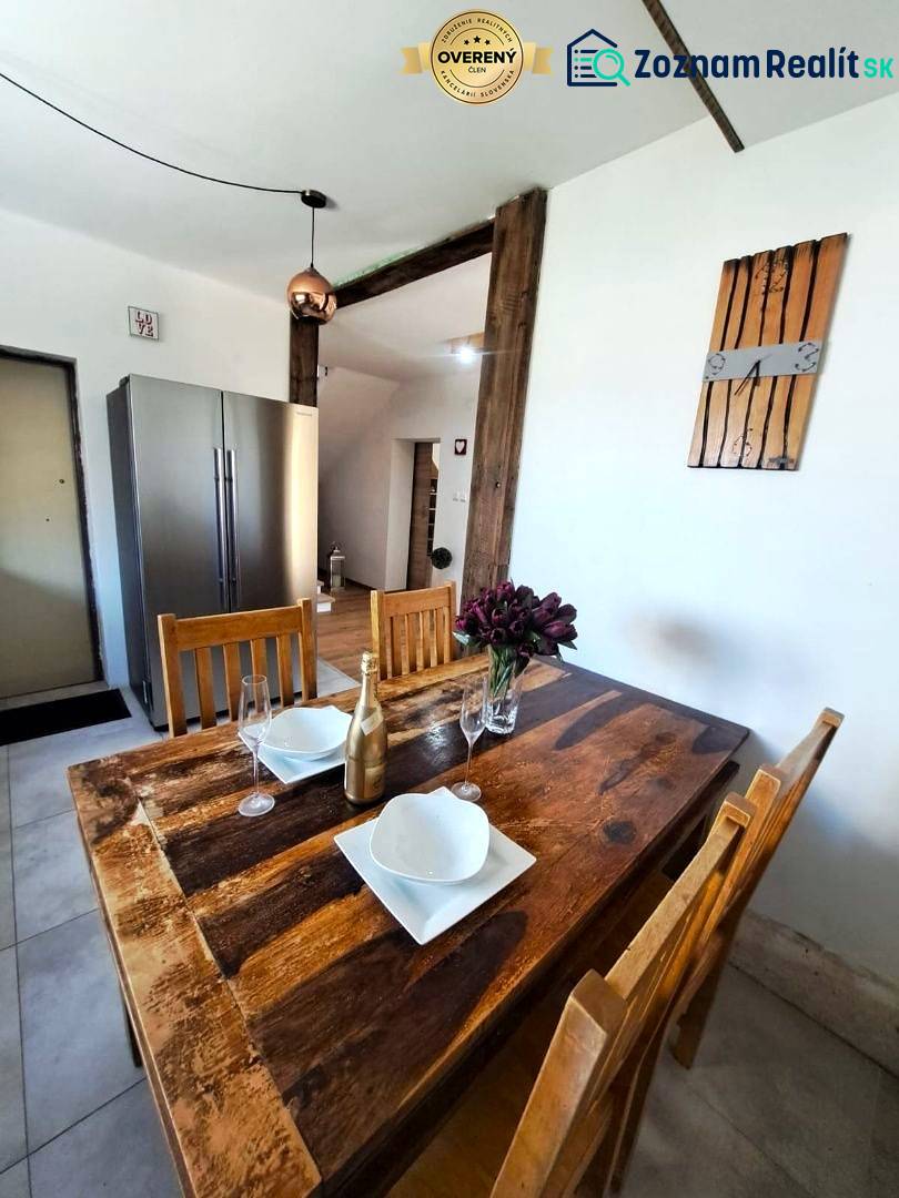 Jídelní stůl s doplňky a lednička v kuchyni rodinného domu.
