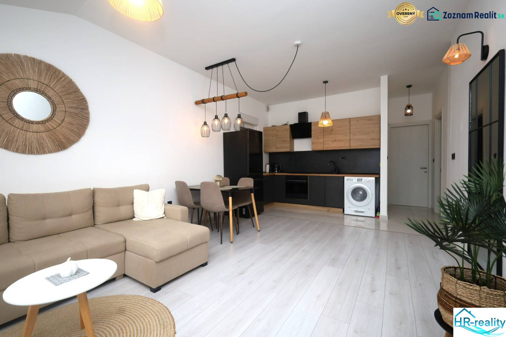 Rekreační apartmán s podlahou s dřevěným dekorem, rohovou sedačkou a moderní kuchyní.